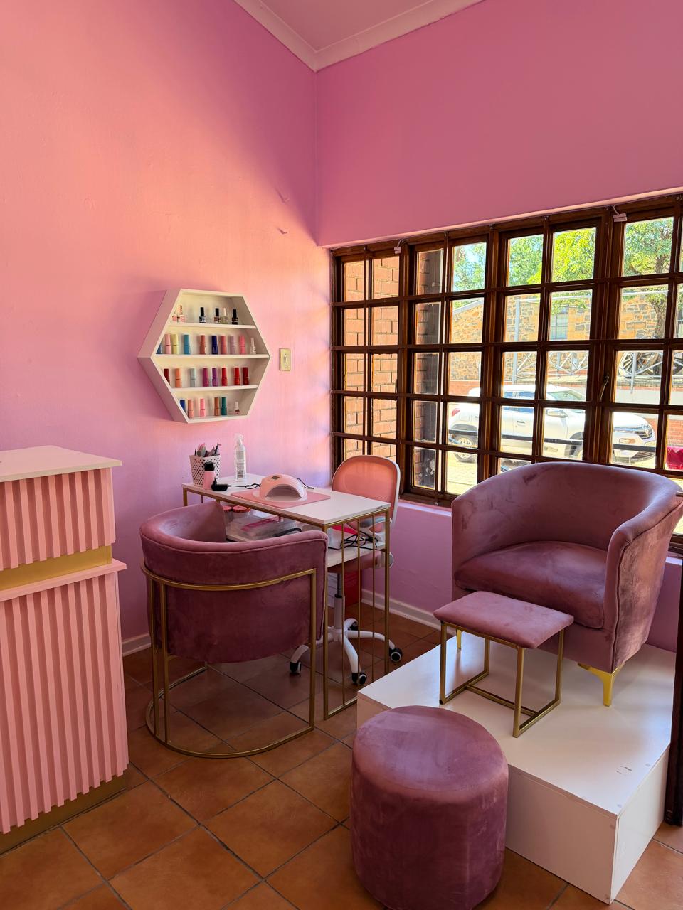 Interior view of Leah's Beautihaus with pink walls and manicure setup